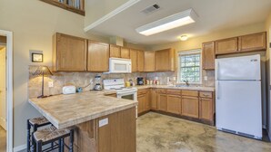 Une cuisine avec des meubles de rangement en bois, un réfrigérateur blanc, un four à micro-ondes, une cuisinière et un évier.