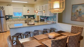 Una cocina moderna con armarios blancos, encimera de granito y una isla central con taburetes de bar.