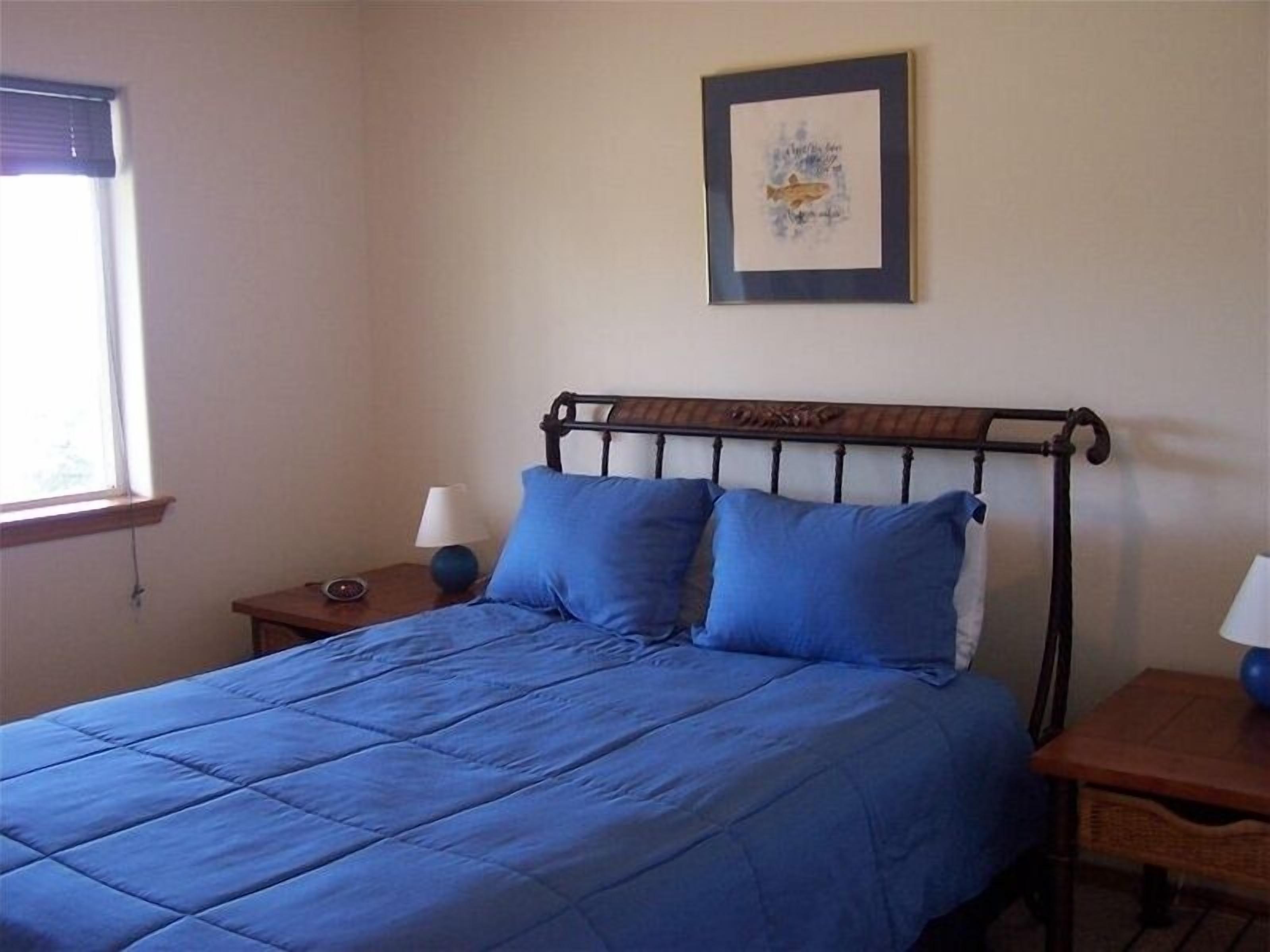 A bedroom with a bed, a nightstand, a lamp, and a framed picture on the wall.