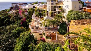 Une propriété située sur la côte, comprenant plusieurs bâtiments, dont une structure principale dotée d’un balcon et une annexe plus petite.