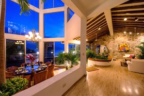 Un intérieur spacieux comprenant un coin repas, un mur en pierre et une vue sur le ciel nocturne.