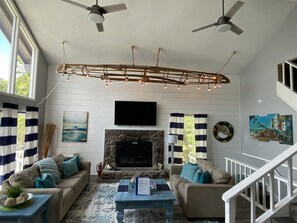 A living room with a fireplace, two sofas, a coffee table, and a ceiling fan. - Next to Margaritaville 5 Bedroom Lakefront House w (Osage Beach)