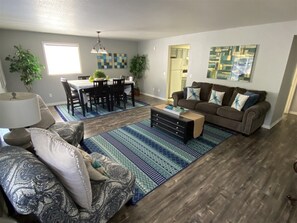 A living room with a sofa, coffee table, and a dining area with chairs and a table.