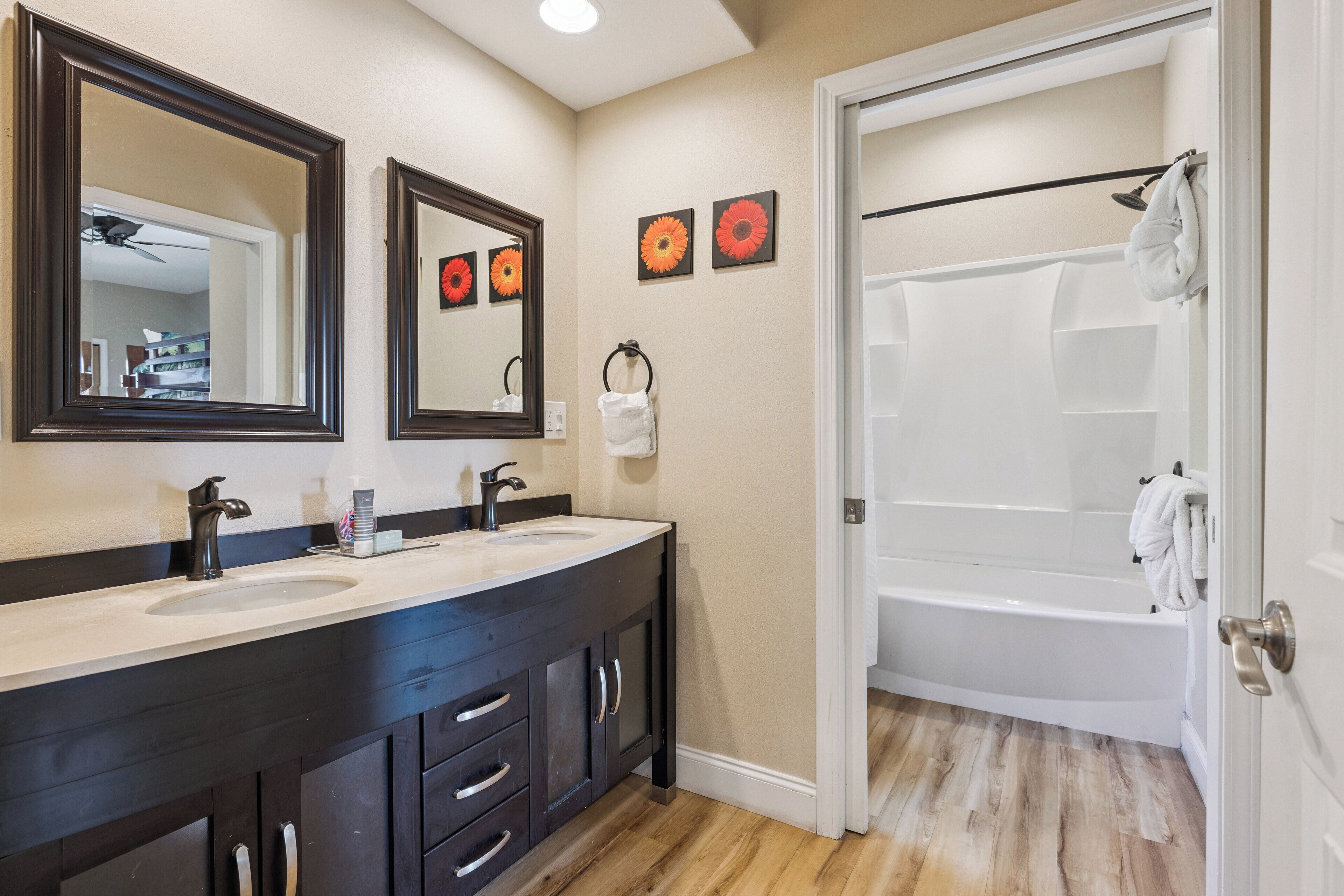 A bathroom with two sinks, a bathtub, and a door leading to another room.