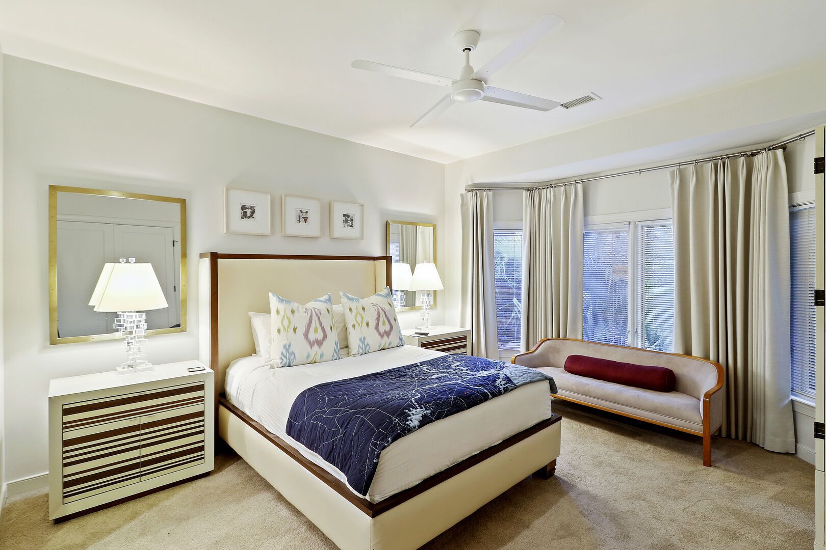 A hotel room with a large bed, a bedside table with a lamp, a chair, and a ceiling fan.