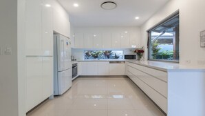 Una cocina moderna con armarios blancos, horno integrado, microondas y ventana con vistas a zonas verdes.