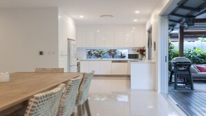 Una cocina moderna con armarios blancos, un microondas integrado y un amplio ventanal con vistas a un jardín.