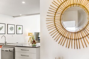 A modern kitchen with a dishwasher, sink, and a decorative wall piece.
