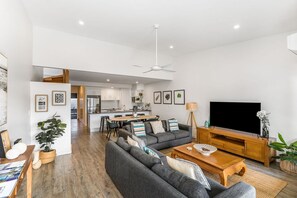 Un salon moderne avec un canapé gris, une table basse en bois et un téléviseur à écran plat.