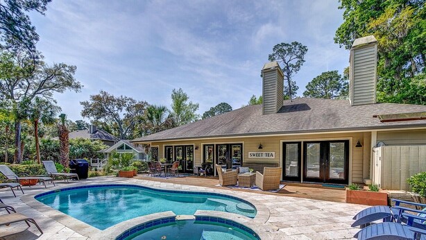 Ein Garten mit Schwimmbecken, Whirlpool und überdachter Terrasse.