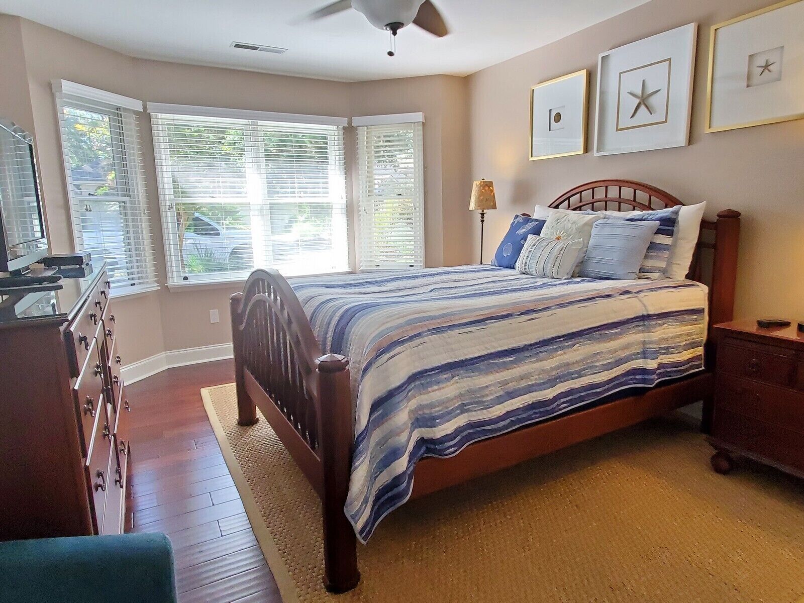 A bedroom with a bed, dresser, and a desk with a lamp.