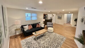 A modern living room with a black sofa, a coffee table, and a patterned rug. -  Fully Furnished Apartment 2 Bedroom-Special rates for 30-night stays or more (Rochester)