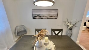 A dining area with a dark wooden table, two chairs, a vase with branches, a candle, and a tray with a rock. -  Fully Furnished Apartment 2 Bedroom-Special rates for 30-night stays or more (Rochester)
