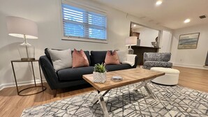 A modern living room with a black sofa, patterned rug, and a coffee table. -  Fully Furnished Apartment 2 Bedroom-Special rates for 30-night stays or more (Rochester)