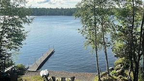 Vista de un lago con muelle, sillas y una zona de césped.