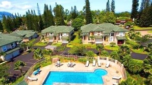 En resort med flere huse i bungalowstil, en central swimmingpool og frodig beplantning.