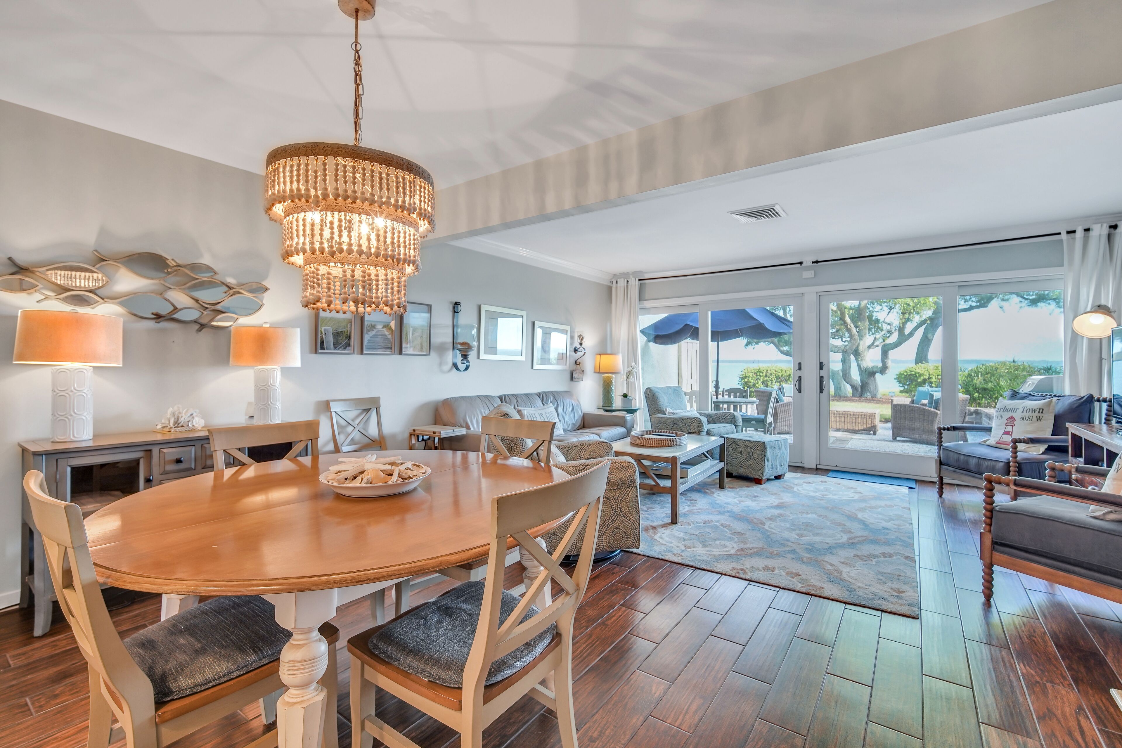 A spacious living area with a wooden dining table, comfortable seating, and a large window offering a view of the outdoors.