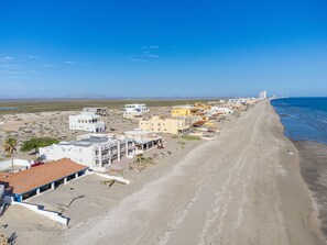 Un pueblo costero con edificios a lo largo de la playa, un cielo despejado y vistas al océano.
