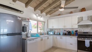 A modern kitchen with white cabinets, stainless steel appliances, and a tiled backsplash.