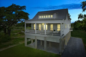 Ein zweistöckiges Wasserrandhaus mit Balkon, großen Fenstern und einer Veranda.