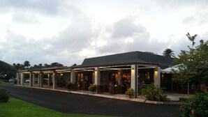A restaurant with outdoor seating, covered by a roof, and surrounded by greenery. -  Location! Golf, Swim, Surf & WALKING distance to Hotel and beaches. (Kahuku)
