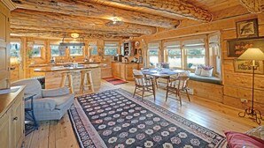 A rustic cabin interior with a kitchen, dining area, and seating.