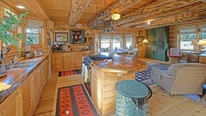 A rustic cabin interior with a kitchen, dining area, and living room.