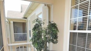 Ein Balkon mit Topfpflanze, zwei Stühlen und einem kleinen Tisch.