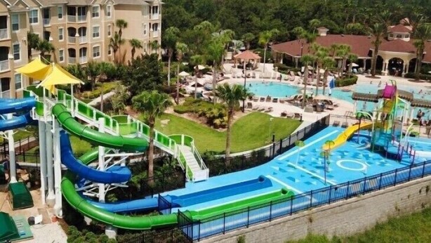 Ein Wasserpark mit mehreren Rutschen und Pools, umgeben von Gebäuden und Grünflächen.