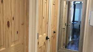 A hallway with wooden doors and a mirror reflecting a room.