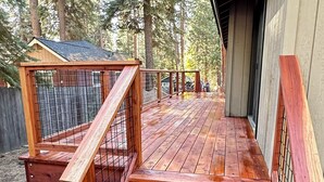 A wooden deck with a metal railing, leading to a covered area with a wooden bench.