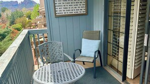A balcony with a table and chairs, a view of the mountains, and a sign with a quote.