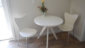 A modern room with a round white table and two white chairs with metal legs. - Furnished detached garden cottage (SF)