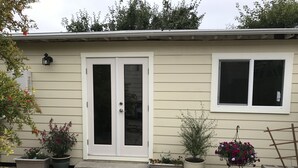 A house with a front door, a window, and potted plants. - Furnished detached garden cottage (SF)
