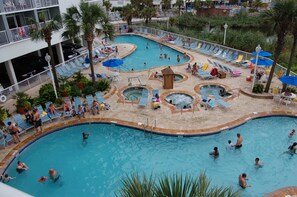 A multi-level pool area with various water features and lounge chairs. - Modern Oceanfront Corner Retreat with Panoramic Views (Myrtle Beach)