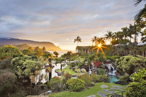 A resort with a pool, palm trees, and a waterfall.