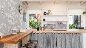 Una cocina con encimera de madera, cortina a rayas y vista al exterior.