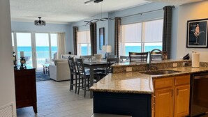 A modern kitchen with a granite countertop, stainless steel appliances, and a view of the ocean.