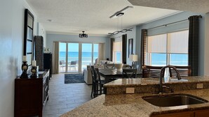 A modern kitchen with a granite countertop, a sink, and a dining area with a view of the ocean.