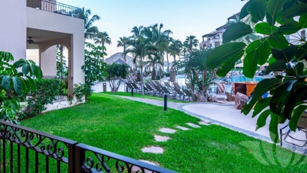 Un patio con piscina, palmeras y un edificio moderno con balcones.