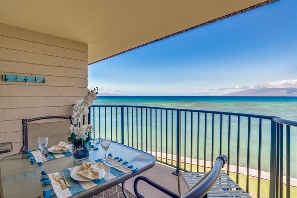 Enjoy a serene ocean view from this balcony, complete with a dining table and comfortable seating.