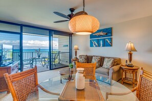 Relax in this inviting living area with a large glass table, comfortable sofa, and wicker chairs.