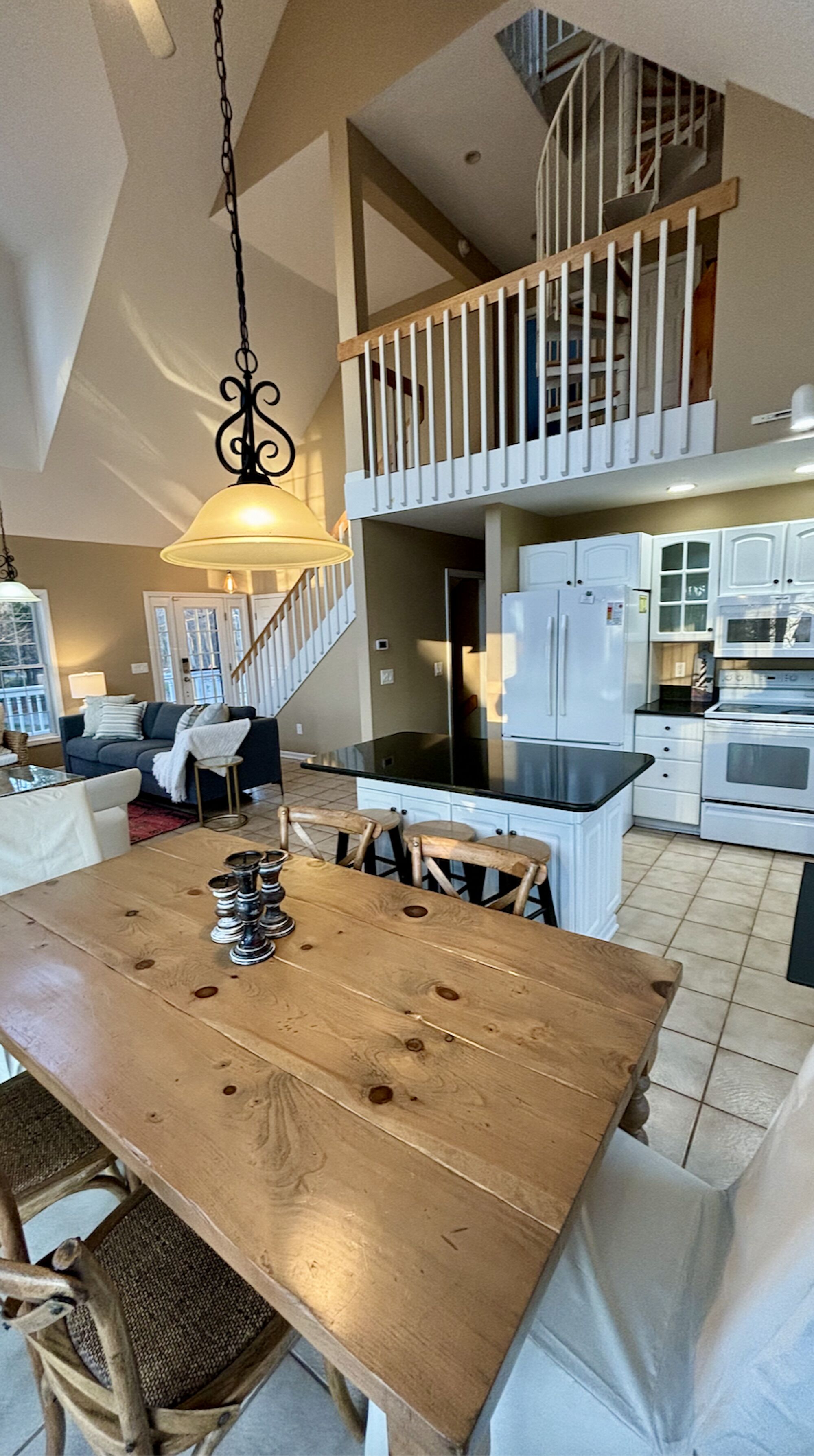 A spacious kitchen with a central island, white cabinetry, and a visible staircase leading to an upper level.