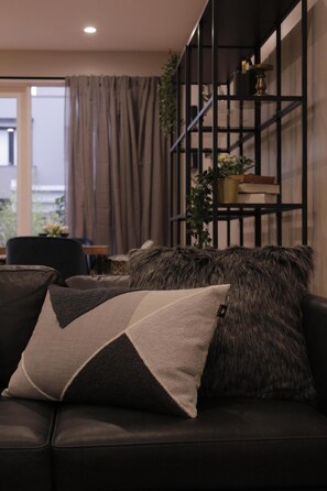 Relax in this stylish living room with a comfortable sofa, bookshelf, and potted plant.