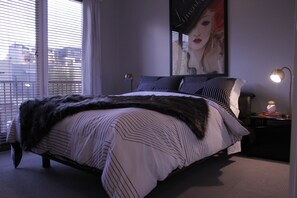 Relax in a serene bedroom with a large bed, nightstand, and a beautiful view through the large window.