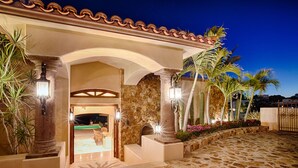 A building with a stone facade, arched entrance, and outdoor seating area. - Villa Gran Vista - Gorgeous Panoramic Ocean Views Villa (Cabo San Lucas)