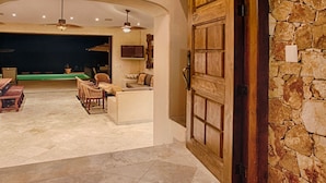 A spacious lobby with a stone wall, a large wooden door, and two turtle wall art pieces. - Villa Gran Vista - Gorgeous Panoramic Ocean Views Villa (Cabo San Lucas)