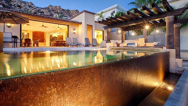 A swimming pool with a pergola and lounge chairs, a patio area with a table and chairs, and a view of the surrounding landscape. - Villa Gran Vista - Gorgeous Panoramic Ocean Views Villa (Cabo San Lucas)