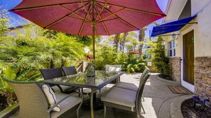 Relax in style with a glass-top table surrounded by wicker chairs under a spacious umbrella.