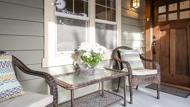 A glass-top table with wicker chairs and a vase of flowers on a porch. - Green Gables-2 Fireplaces,Salt Hot tub, 100+mbps Wifi, AC, Bikes, Big Yard,Walk! (Bend)